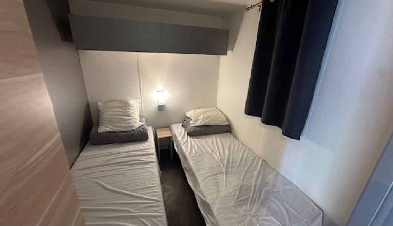 La chambre avec 2 lits simple du mobil-home O’hara 784 dans le Jura en location au Camping le Val d’Amour