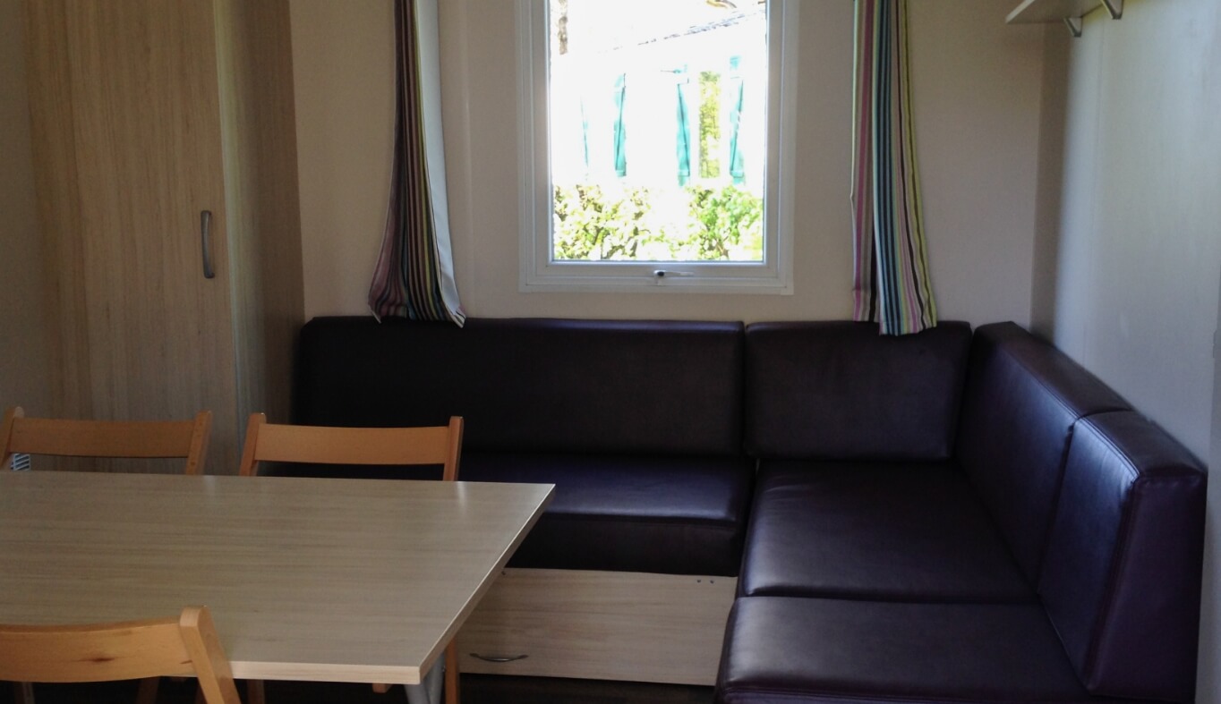 Salon avec banquette du mobil-home Super Titania dans le Jura en location au Camping le Val d’Amour
